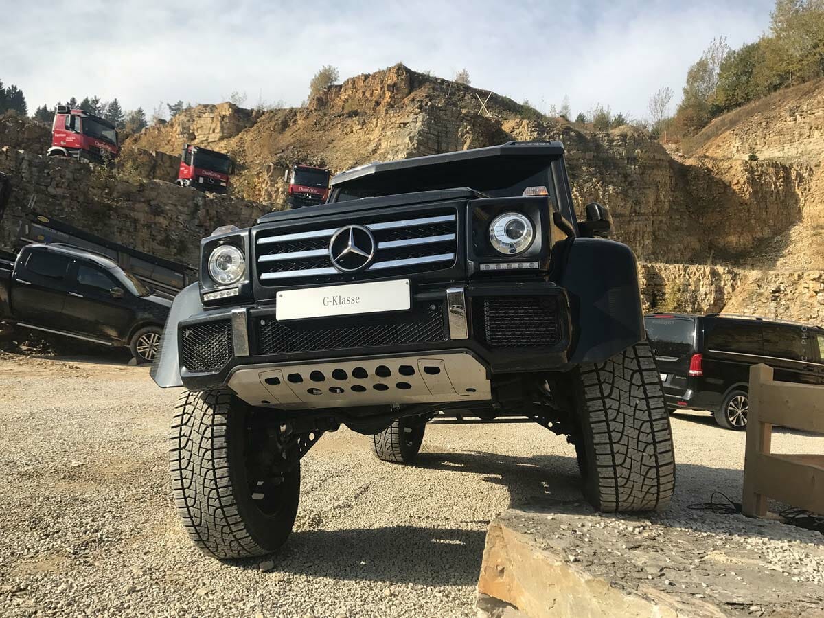 Un todoterreno negro está con un neumático sobre una piedra en un entorno arenoso.