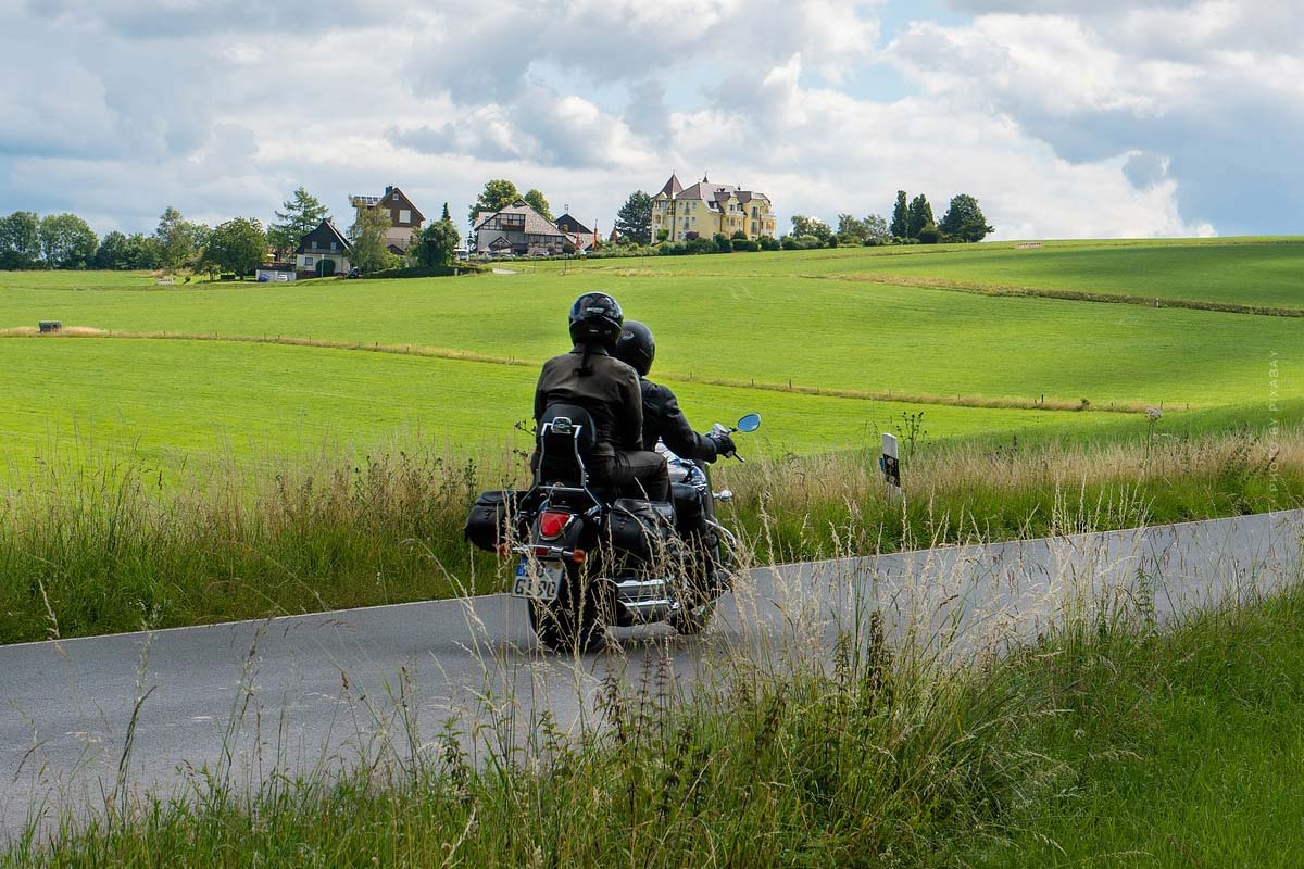 Dos personas están sentadas en una moto que pasa por un prado verde