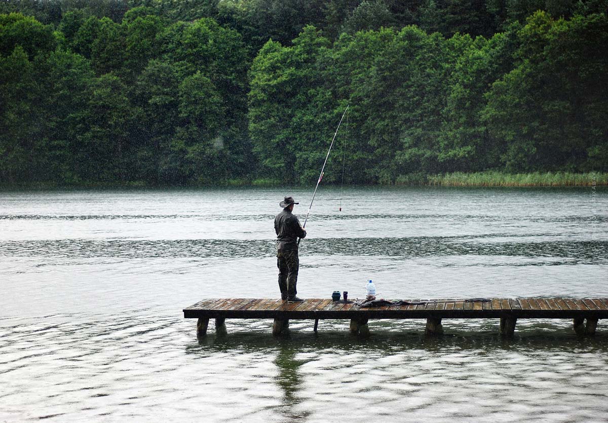 Un pescador está de pie en un estanque en el lago