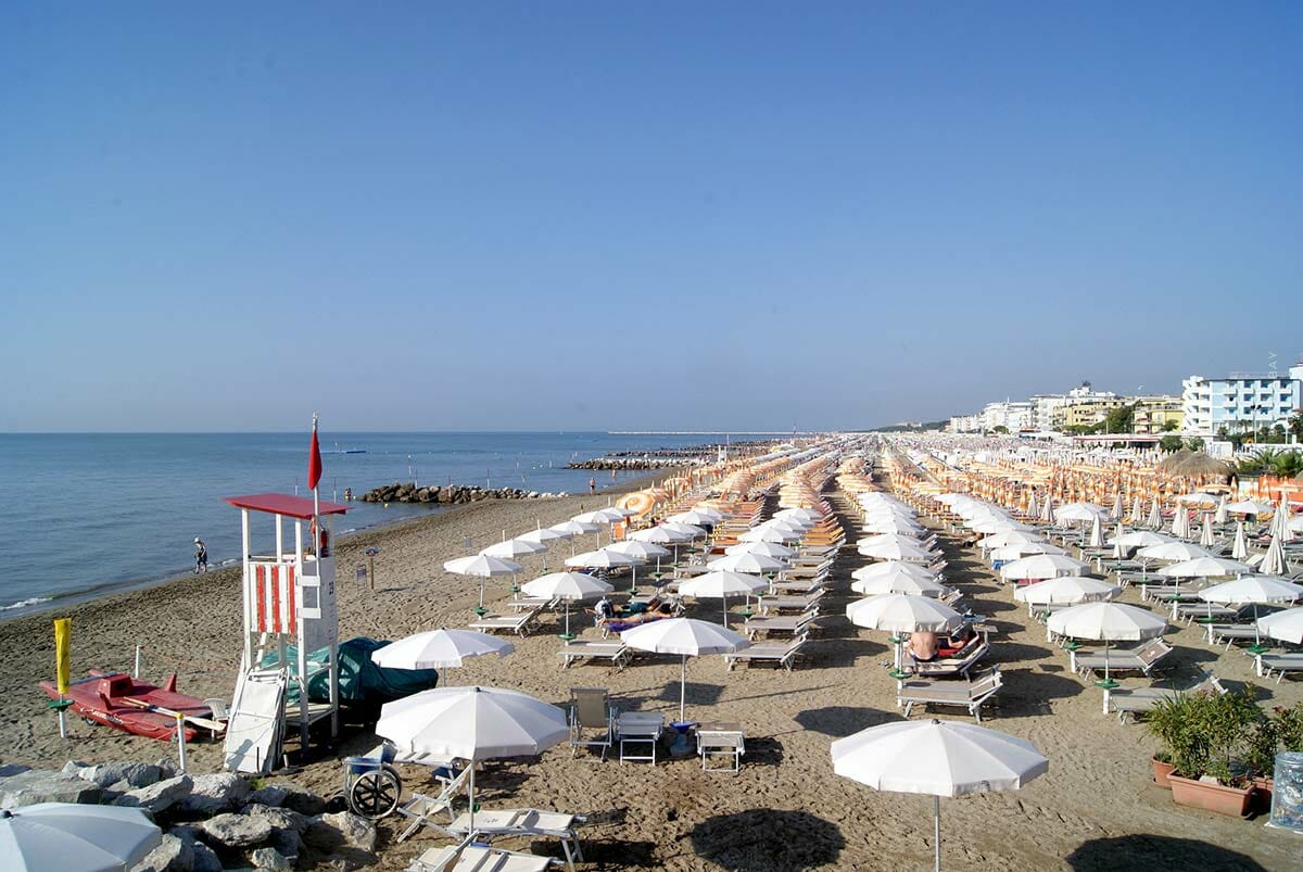 Sombrillas blancas extendidas en una playa de arena junto al mar azul