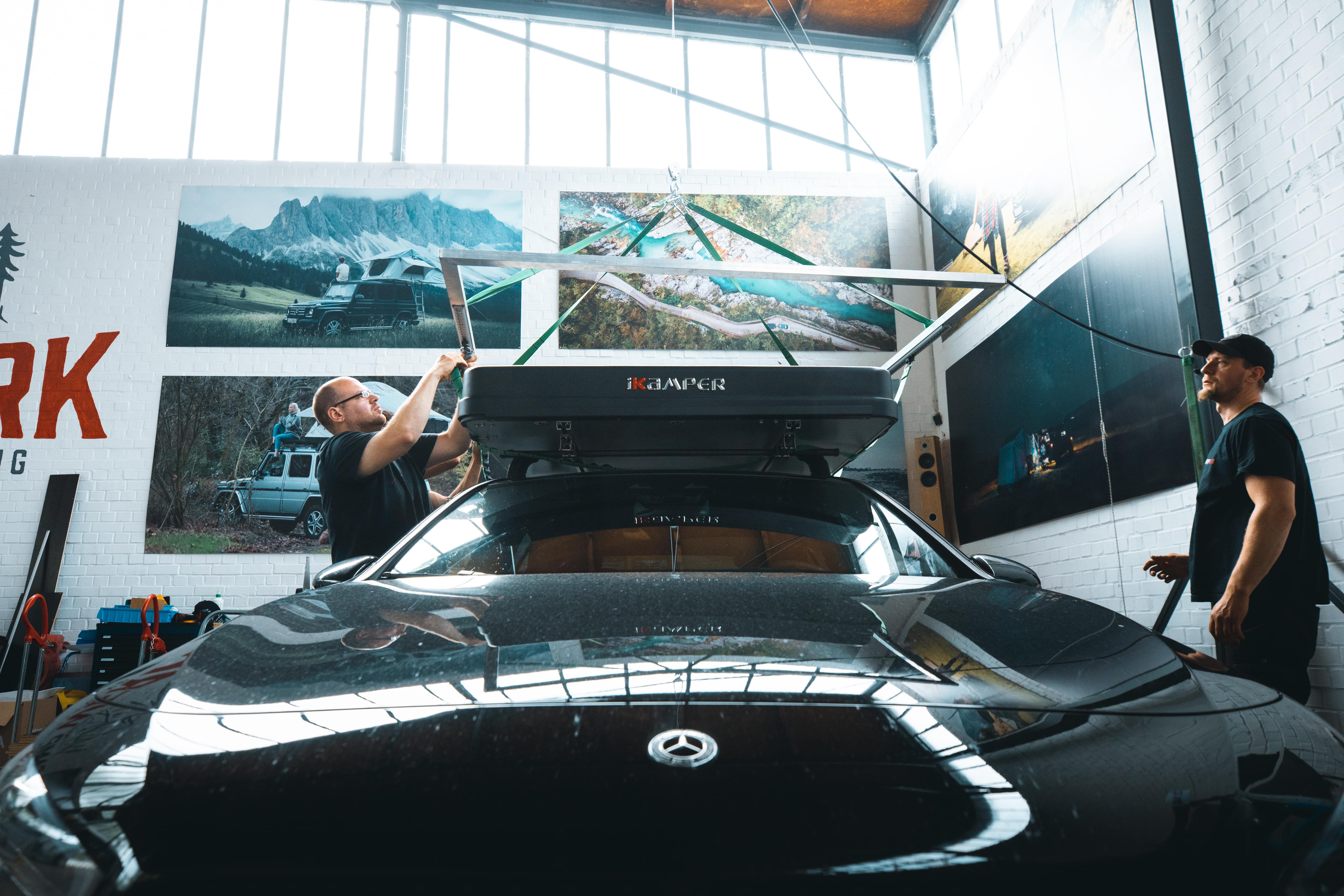Empleados de CAMPWERK montando una tienda de techo en un coche negro