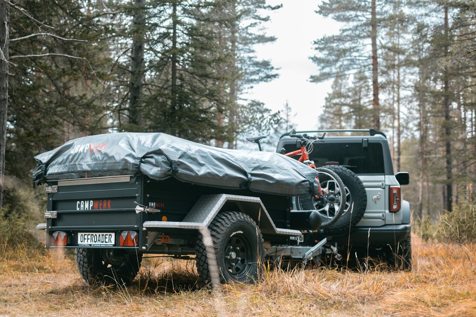 Un coche con un remolque tienda desenganchado en un camino forestal